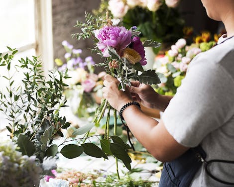 Pink and gold flowers are gently placed in a glass vase